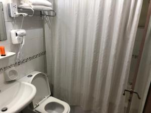 bagno con tenda da doccia bianca e servizi igienici di New Royal Mark Hotel Apartments a Dubai
