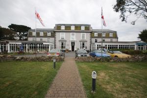 un gran edificio blanco con coches estacionados frente a él en La Trelade Hotel en St Martin Guernsey