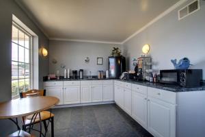 a large kitchen with white cabinets and a table at Key West Inn - Childersburg in Childersburg