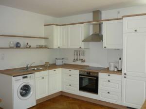 a kitchen with white cabinets and a washing machine at Ferienwohnung Elke Eggers in Wallsbüll
