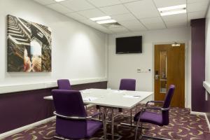 a conference room with a table and purple chairs at Holiday Inn Express Dunstable by IHG in Dunstable