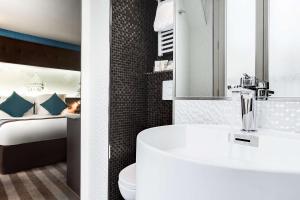 a bathroom with a sink and a bedroom with a bed at Best Western Nouvel Orl&eacute;ans Montparnasse in Paris