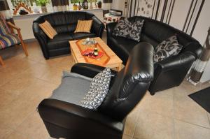 a living room with black leather chairs and a table at Ferienwohnung Anni, 65325 in Moormerland