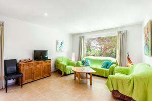 uma sala de estar com dois sofás verdes e uma televisão em Casa Antonio Invierno em Cala Llombards