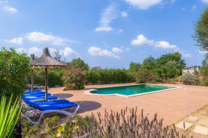 a swimming pool with blue lounge chairs and an umbrella at Geminis in Llucmajor