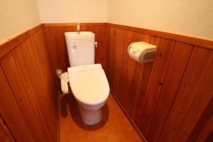 a bathroom with a white toilet in a wooden wall at Guest House Hitsujian in Kyoto