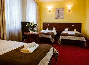 pokój hotelowy z 2 łóżkami i wazonem kwiatów w obiekcie Hotel Piotr Spa&Wellness w mieście Boguszów-Gorce