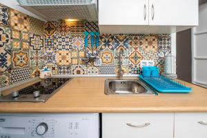 a kitchen with a sink and a tile wall at Casa Triana in Vejer de la Frontera