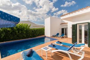 een villa met een zwembad en tuinmeubilair bij Villa Eduard in Binibeca