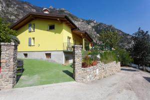 una casa gialla con un muro in pietra e un cortile di Casa Vacanze Marisol a Tremosine Sul Garda