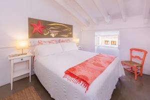 1 dormitorio con cama blanca, mesa y silla en Villa Ithaka Petit, en Artà