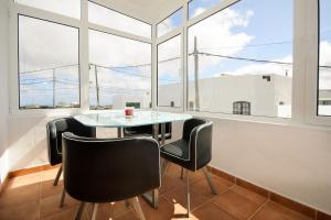 uma mesa e cadeiras num quarto com janelas em Apartamento Ye em Haría