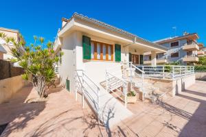 Casa blanca con persianas verdes y escaleras en S Olivera, en Can Picafort
