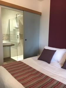 a bedroom with a bed and a glass shower at Le Moulin de Lassalle in Curemonte