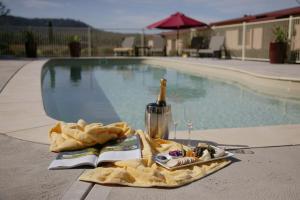 uma mesa com uma garrafa de vinho e um livro ao lado de uma piscina em Nightingale Villas em Broke