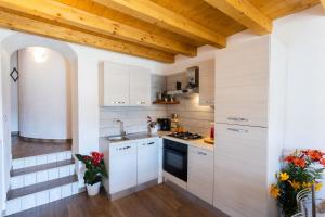 una cucina con armadi bianchi e soffitto in legno di Artù a Tremosine Sul Garda