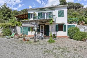 a house with green shutters and a yard at Il giardino nel sole Trilo in Capoliveri