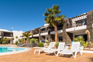 un complejo con sillas blancas y piscina en Apartamento Relax, en Puerto del Carmen