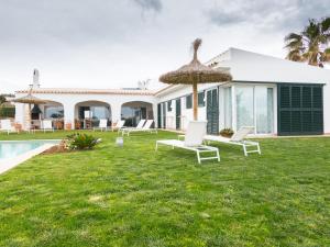 a villa with a yard with chairs and an umbrella at Villa De Lujo Frente A La Playa in Binisafua