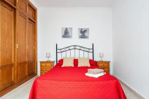 sypialnia z czerwonym łóżkiem i drewnianymi szafkami w obiekcie Apartamento Doña Alba w mieście Conil de la Frontera