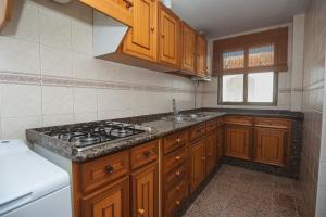 uma cozinha com armários de madeira e um forno com placa de fogão em Apartamento Ramón em Conil de la Frontera