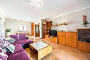 a living room with a purple couch and a tv at Villa Dos Estels in Cala d´Or