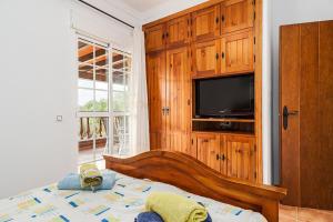 a bedroom with a bed with a tv and a wooden cabinet at Casa de Piedra in El Cañal