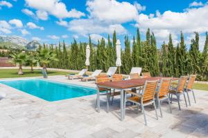 eine Terrasse mit einem Holztisch und Stühlen neben einem Pool in der Unterkunft Ses Rentadores in Selva