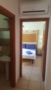 ein Schlafzimmer mit einem Bett und ein Badezimmer mit einem Waschbecken in der Unterkunft Bilocale centralissimo vista mare 29 in Torre dell'Orso
