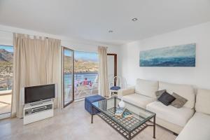 a living room with a white couch and a tv at Apartamento Mirador 6i in Cala de Sant Vicent