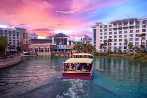 ein Boot, das einen Fluss hinunter vor einem Hotel fährt in der Unterkunft Universal's Loews Sapphire Falls Resort in Orlando