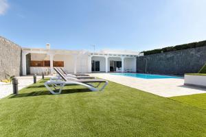 a white villa with a yard with a swimming pool at Casa Mercedes in Yaiza