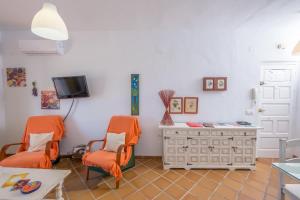 コニル・デ・ラ・フロンテーラにあるLas Vistas del Último Paraísoのリビングルーム(オレンジチェア2脚、テレビ付)