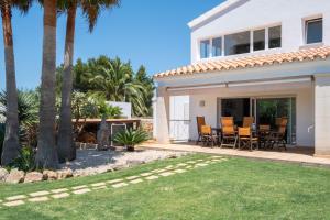 a white house with palm trees and a patio at Abatzer in Ciutadella