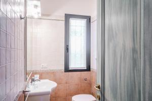 un bagno con un water, un lavandino e una finestra di Residenza Fiorella a San Pantaleo Altre 20 foto