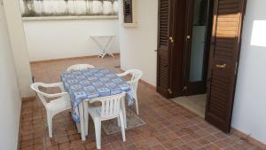 einen Tisch mit weißen Stühlen und einem blauen und weißen Tisch in der Unterkunft Bilocale 50 mt. dalla spiaggia 27 in Torre dell'Orso