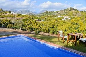 a swimming pool with a table and a view of a mountain at Casa entre Nerja y Frigiliana in Frigiliana