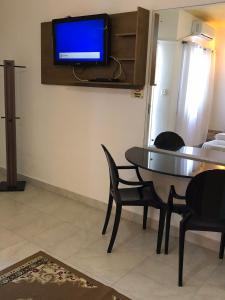 a dining room with a table and a tv on a wall at Motel Del Fuego (Adult Only) in Pelotas