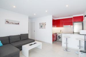 uma sala de estar com um sofá e uma cozinha com armários vermelhos em Villa Aday and Ixeia em Cala Blanca