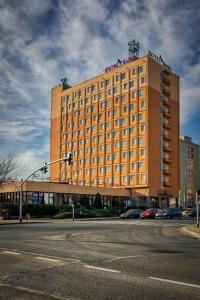 duży pomarańczowy budynek na rogu ulicy w obiekcie Hotel Konin w Koninie