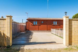 a brown house with a fence and a driveway at Las tres hermanas in Conil de la Frontera