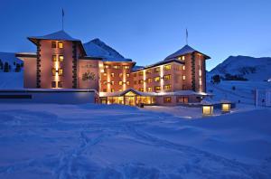 a large building in the snow at night at Hotel Alpenrose aktiv & sport in Kühtai