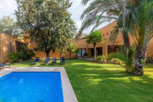 a courtyard with a swimming pool and palm trees at Villa Cala Bona in Cala Bona