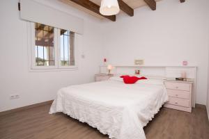 ein weißes Schlafzimmer mit einem Bett mit einem roten ausgestopften Tier darauf in der Unterkunft Can Ferrer in Alcúdia