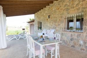 eine Terrasse mit einem Tisch, Stühlen und einer Steinmauer in der Unterkunft Can Ferrer in Alcúdia