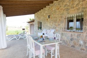 d'une terrasse avec une table et des chaises ainsi qu'un mur en pierre. dans l'établissement Can Ferrer, à Alcúdia