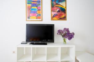 TV en un puesto blanco en una habitación con pinturas en Casa Bonita Argana en Arrecife