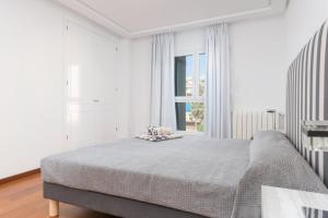 a white bedroom with a large bed and a window at Marítimo 46 in Alcudia
