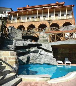 a swimming pool with a waterfall in front of a building at Hotel Brigitte in Sighnaghi