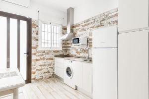 a kitchen with white appliances and a brick wall at Apartamento Claudia in Conil de la Frontera